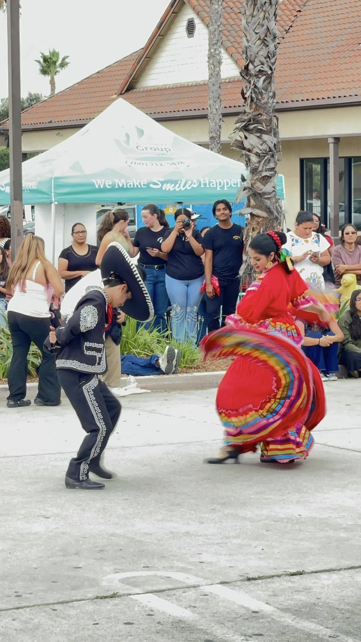 Two folklorico dancers performing in traditional dress at the community celebration