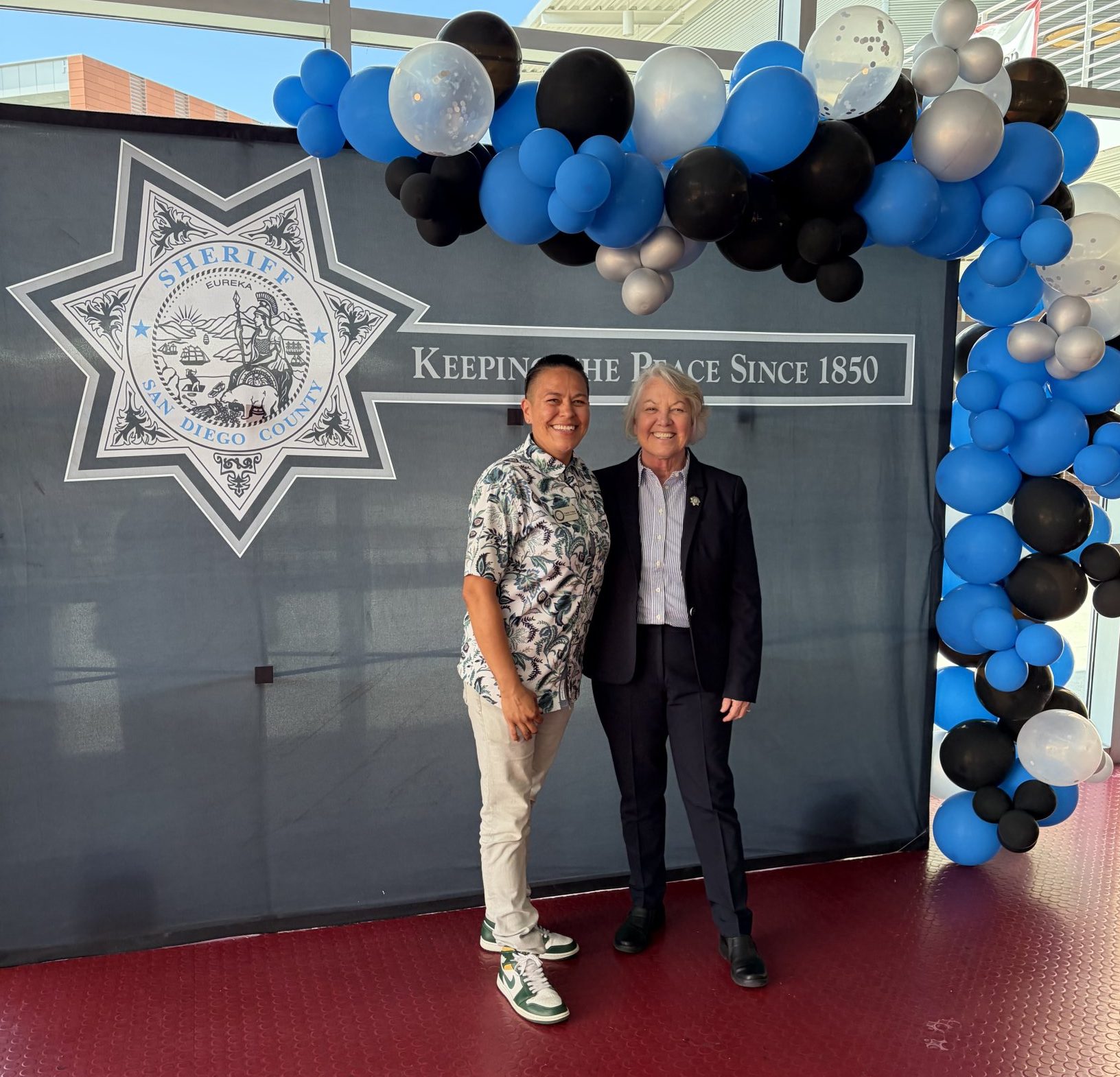 Two event attendees in front of the San Diego County Sheriff backdrop