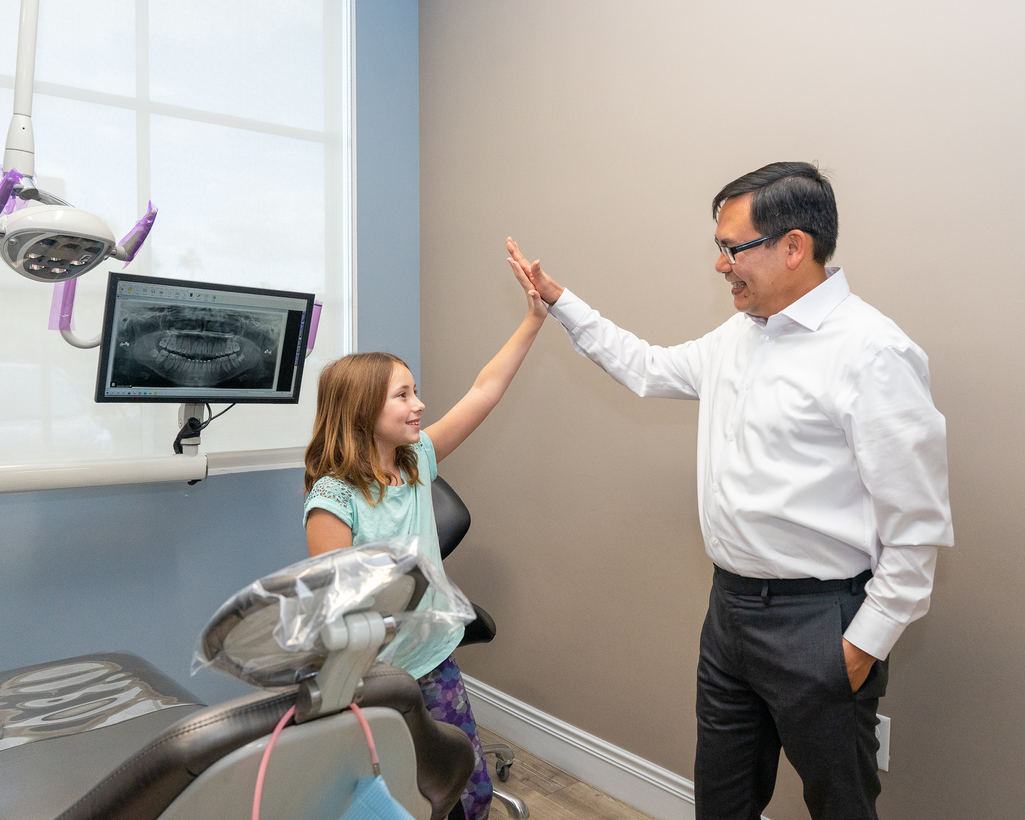 Dr. Vinh Le sharing a high-five with a child in the dental office
