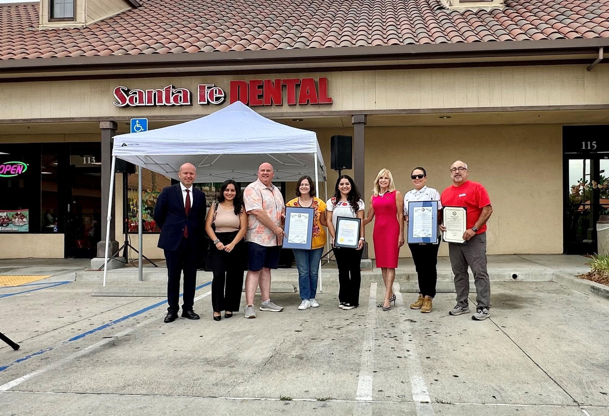 Community celebration participants holding certificates outside Santa Fe Dental Group